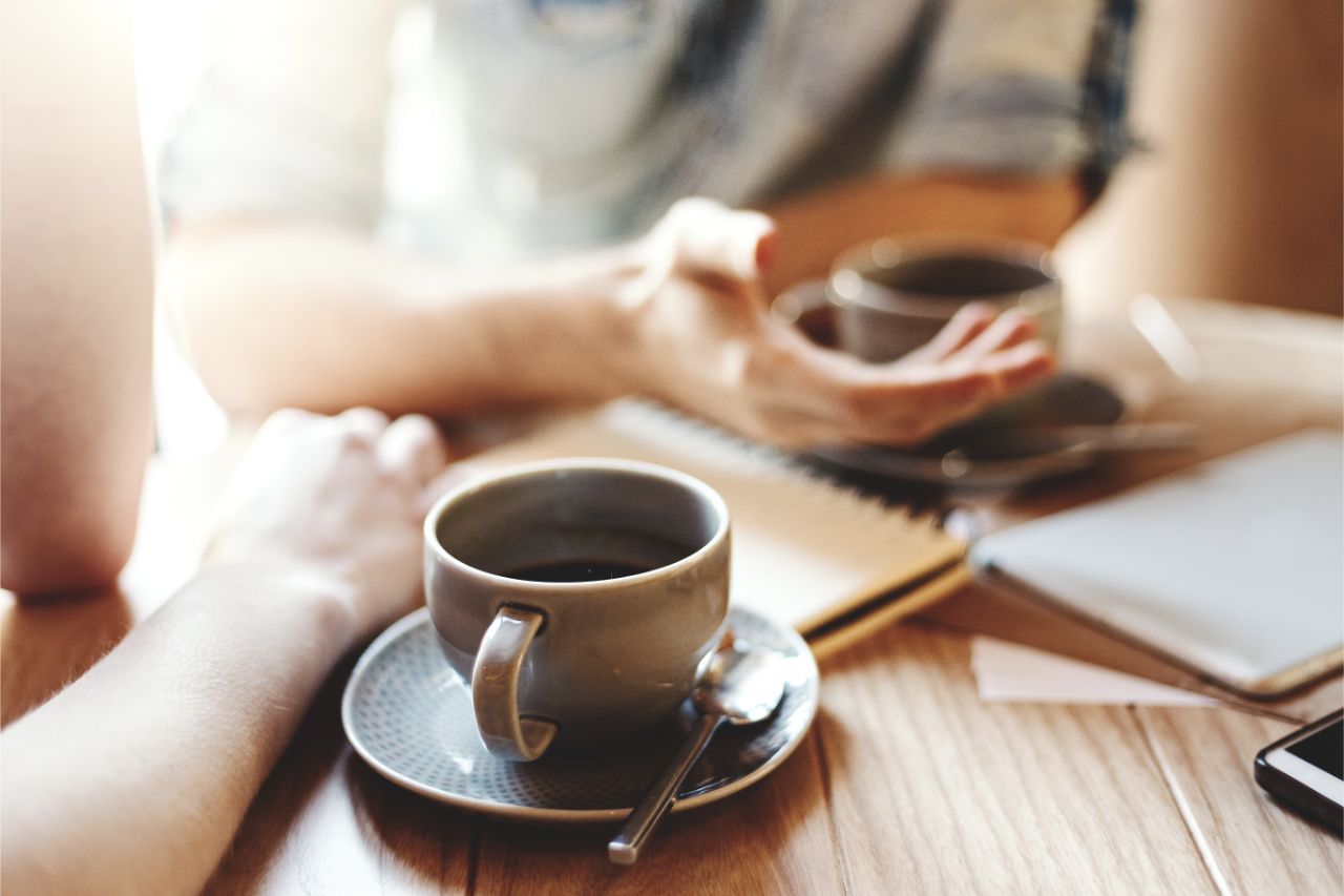 Friends talking at cafe table during coffee break.